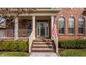 Inviting front porch with classic brick steps, white pillars, and an American flag adds charm at 4030 Statesmen Dr, Indianapolis, IN 46250
