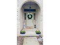 Inviting front door entrance with wreath, transom windows, and brick archway, decorated with planters at 5949 Willow Bend Dr, Avon, IN 46123