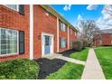 Close-up exterior view featuring a brick townhome with a blue door and green landscaping at 6515 Park Central Way # B, Indianapolis, IN 46260