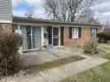 Charming brick and vinyl exterior with a concrete patio, features a security door and mature shrubbery at 6808 Summer Time Dr, Indianapolis, IN 46226