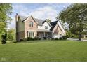 Charming two-story brick home with a well-manicured lawn, mature trees, and attached three car garage at 1143 N Sugar Bend Run, Greenfield, IN 46140