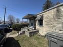 Stone home featuring a covered porch with striped awning, complemented by lush greenery at 1515 S Emerson Ave, Indianapolis, IN 46203