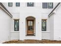 Close up view of the front door and entryway of a new home with painted white brick and contrasting wood door at 19909 Windsor Park Blvd, Westfield, IN 46069