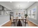 Sunlit dining room featuring hardwood floors, modern chandelier, and a view into the kitchen area at 2920 E 11Th St, Indianapolis, IN 46201