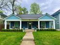 Inviting blue bungalow with a welcoming front porch and manicured landscaping at 3535 Birchwood Ave, Indianapolis, IN 46205