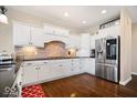 A well-appointed kitchen showcasing white cabinetry, stainless steel appliances, a brick backsplash, and hardwood flooring at 368 Westbrook Ct, Columbus, IN 47201