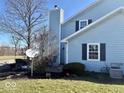 Side view of a charming home showcasing the backyard, chimney, and landscaping at 3934 N Lakeside Dr, Muncie, IN 47304