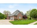 Beautiful brick home with a three-car garage, well-kept lawn, and mature trees at 6010 Fawnwood Dr, Greenwood, IN 46143