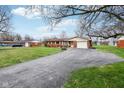 Inviting brick home with attached garage, a long driveway, and a well-maintained green lawn at 6905 E Hanna Ave, Indianapolis, IN 46203