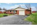 Cozy brick home with attached garage and paved driveway leading up to the charming entrance at 6905 E Hanna Ave, Indianapolis, IN 46203