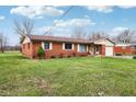 Quaint single-story brick home featuring a green lawn, attached garage, and a welcoming facade at 6905 E Hanna Ave, Indianapolis, IN 46203