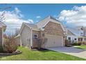 Side view of the home featuring a two-car garage with brick facade and well-kept lawn at 7337 Red Maple Dr, Zionsville, IN 46077