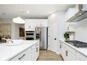 Sleek kitchen featuring white cabinets, stainless steel appliances, center island with quartz countertops, and wood-look flooring at 9403 Watson Way, Avon, IN 46123