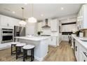 Modern kitchen with white cabinets, stainless appliances, island with seating, and wood-look floors at 9403 Watson Way, Avon, IN 46123