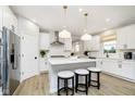 Bright kitchen with white cabinetry, a center island with seating, stainless steel appliances, and wood-look flooring at 9403 Watson Way, Avon, IN 46123
