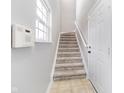 Inviting staircase with neutral carpet, white trim, and a nearby window for natural light at 1160 Falcon Rdg, Carmel, IN 46280
