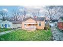 View of a charming one-story home featuring a quaint front porch and lush green lawn at 1940 N Drexel Ave, Indianapolis, IN 46218