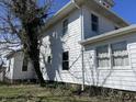 A side view of a two-story white home, showing the yard with blooming flowers in spring at 238 S Main St, Wilkinson, IN 46186