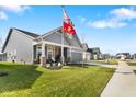 Charming gray home with a well manicured lawn, welcoming front porch, and flags on a sunny day at 3121 Arkle Rd, Westfield, IN 46074