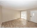 Open living area featuring wood floors, neutral paint, and a bright front door at 4008 N Mitthoefer Rd, Indianapolis, IN 46235