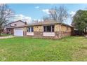 A well-maintained ranch-style home with a stone facade, green lawn, and mature trees at 4911 Carry Back Ln, Indianapolis, IN 46237