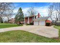 A brick two-story home with mature trees, a two-car garage, and a manicured lawn at 6537 Grosvenor Pl, Indianapolis, IN 46220