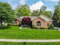 Well-kept brick home boasting a vibrant red maple tree and manicured bushes at 7732 Ashtree Dr, Indianapolis, IN 46259