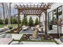 Cozy outdoor seating area featuring a wooden pergola, modern furniture, and natural stone landscaping at 11003 Holliday Farms Blvd, Zionsville, IN 46077