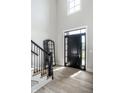Bright foyer with a dark door, beautiful mirror, stylish staircase, and lovely wood flooring at 12099 Sigillary Way, Carmel, IN 46032