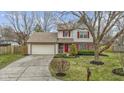 Inviting two-story home with an attached garage, landscaped front yard, and charming red door at 12161 Pebblebrooke Ct, Indianapolis, IN 46236
