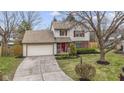 View of a two-story home with red shutters, an attached garage, and a beautifully landscaped yard at 12161 Pebblebrooke Ct, Indianapolis, IN 46236