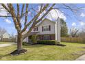 This home has a lush lawn and mature trees, complemented by red shutters and an attached garage at 12161 Pebblebrooke Ct, Indianapolis, IN 46236