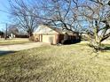 View of the side of home showing the 2-car garage, driveway, and some landscaping at 1645 Woodview Ln, Anderson, IN 46011