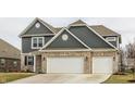 Charming two-story home with brick and siding exterior, a three-car garage and a well-manicured lawn at 4828 W Jamestown Trce, New Palestine, IN 46163