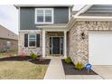 Inviting front entrance with brick accents, black door, and a well-maintained lawn and landscape at 4828 W Jamestown Trce, New Palestine, IN 46163