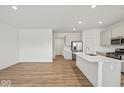 Bright open-concept kitchen with stainless steel appliances, quartz countertops and hardwood flooring, flowing into the living area at 17293 Rancorn Pl, Westfield, IN 46074