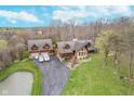 Aerial shot of the property featuring the home, pond, garage, and surrounding trees at 222 Stony Ln, Noblesville, IN 46060