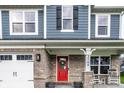 Inviting front porch with rocking chairs, a red front door, and brick accents at 3164 Kent Dr, Brownsburg, IN 46112