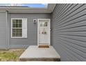 Close-up of the entry door with a wreath and gray siding, accented with a wall-mounted light at 4221 Millersville Rd, Indianapolis, IN 46205