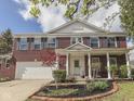 Charming red brick home featuring a welcoming front porch with white columns and a beautifully landscaped front yard at 10343 Waveland Cir, Fishers, IN 46038