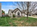 Side yard of home with green lawn, tidy landscaping, and patio area with seating, partially shaded by a mature tree at 1086 Meadowview Ct, Franklin, IN 46131