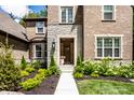 Close up view of the brick home's stone front entrance, featuring a well-manicured garden at 552 E 82Nd St, Indianapolis, IN 46240