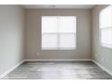 Neutral room featuring gray wood-look flooring, white trim, and two windows at 5786 Blue Sky Dr, Whitestown, IN 46075