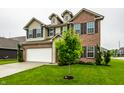 Well-maintained two-story home boasts manicured lawn and landscaping complemented by a two car garage with tan and brick accents at 647 Albermarle Dr, Pittsboro, IN 46167