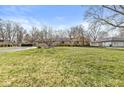 View of the property showcasing the large front yard and exterior details of the single-story home at 8606 Manderley Dr, Indianapolis, IN 46240