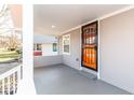 Cozy covered porch with a modern orange security door and ample space to relax and enjoy the outdoors at 1302 S Sherman Dr, Indianapolis, IN 46203