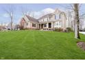 A view of a tan home with a well-maintained lawn, front entrance, and professionally landscaped exterior at 14577 Faucet Ln, Fishers, IN 46040