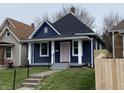 Charming blue house with white trim, gray steps, a black roof and a pink front door at 1518 Lawton Ave, Indianapolis, IN 46203