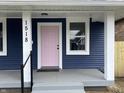 Front porch and pink front door of blue house with white trim and gray steps at 1518 Lawton Ave, Indianapolis, IN 46203