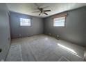 This image displays a bedroom with a ceiling fan, windows, and carpeted flooring at 2115 Leonard Rd, Martinsville, IN 46151